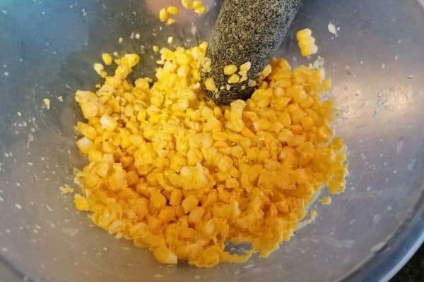sweetcorn kernels being mashed with a mortar