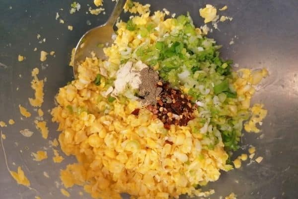 adding spices and herbs into mashed sweetcorn kernels for the fritters