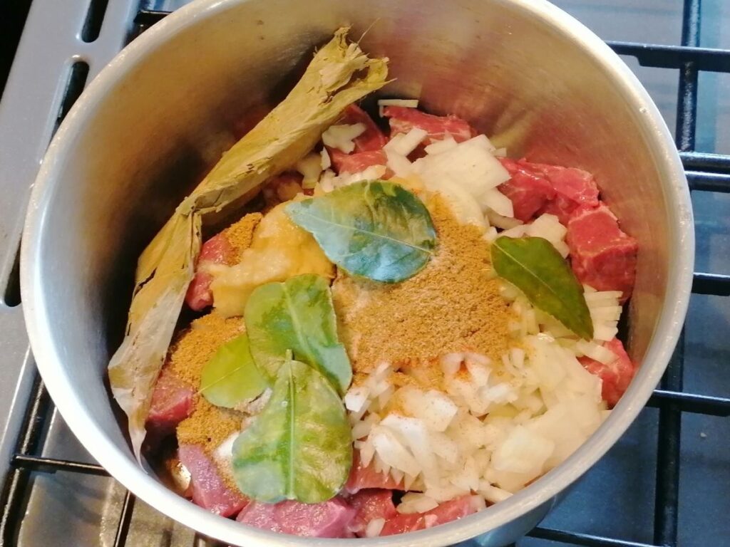 raw beef, spices and herbs in a pot