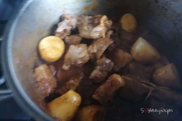 frying potatoes and lamb meat in masala sauce