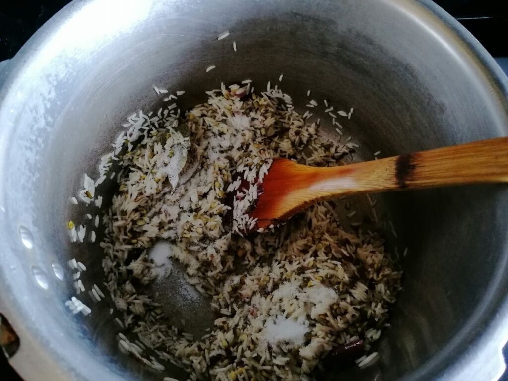 frying the rice, mung beans, and spices to make kitchari