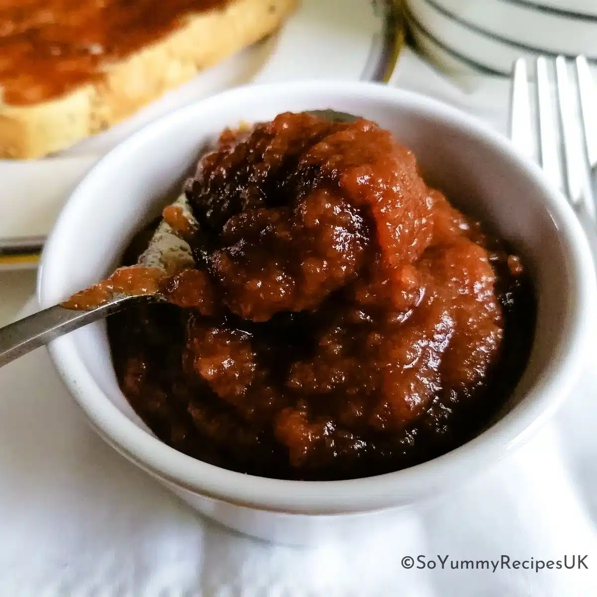 A small bowl of apple jam with a teaspoon over it