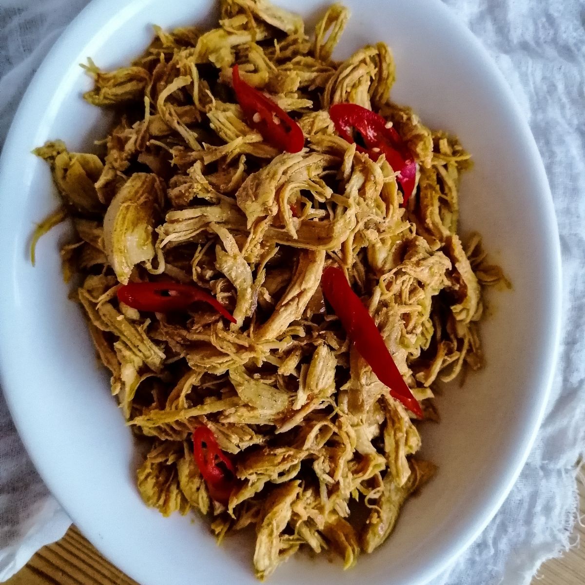 Ayam Suwir Bumbu Bali - shredded chicken with Balinese spices in an oval white dish