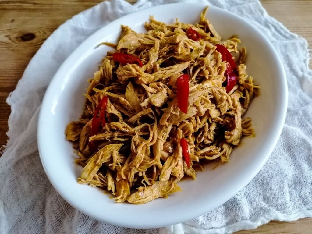 An oval dish of shredded chicken in Balinese spices