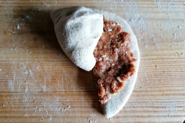 chapati dough with minced meat is being rolled