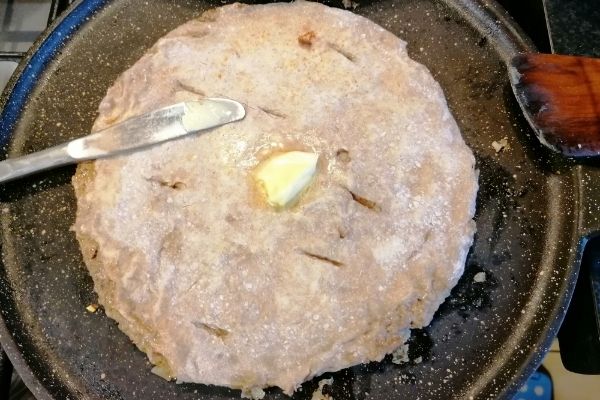 putting a butter on the cooked paratha