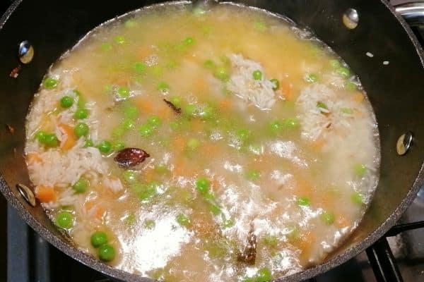 adding water to boil the rice and vegetables 