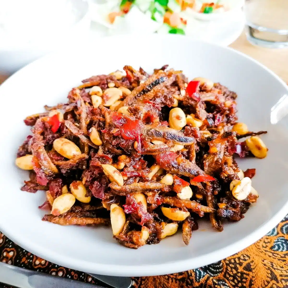 a bowl of dried-anchovies and peanuts in spicy chillies