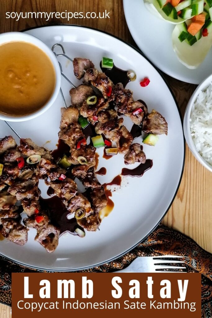 a plate of meat skewers with a bowl of peanut sauce with an overlay text