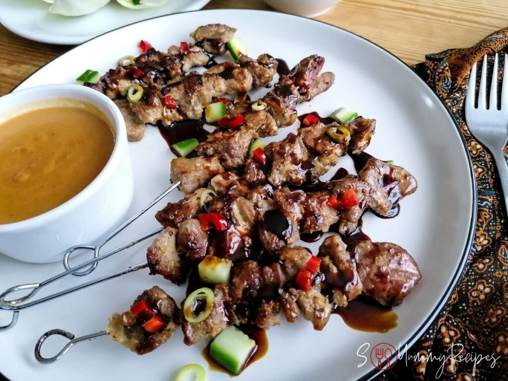 A plate of lamb satay and a bowl of peanut sauce.