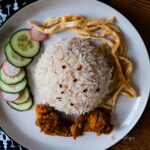 a plate of nasi uduk, cucumber, omelette, and fried chicken