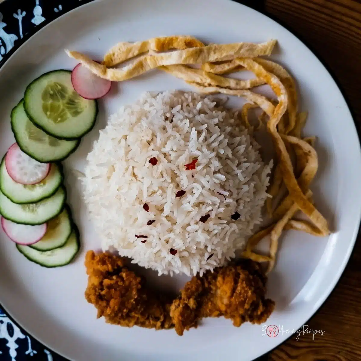 a plate of nasi uduk, cucumber, omelette, and fried chicken