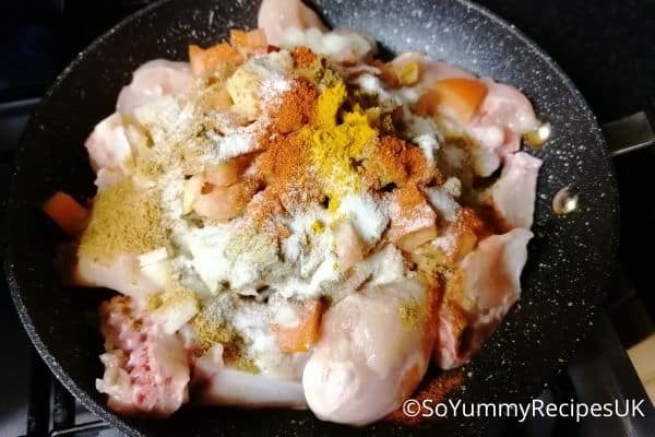 chicken pieces and all spices and herbs in a wok