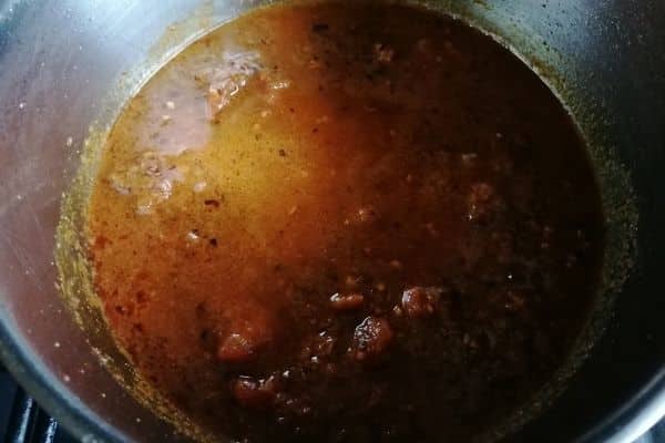 adding canned tomatoes to the spices