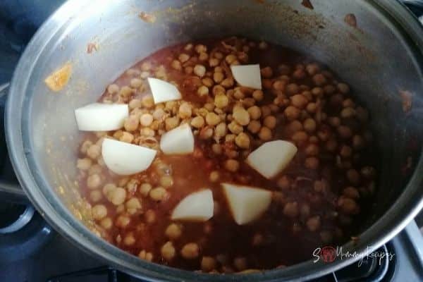 adding potatoes into the chickpea curry