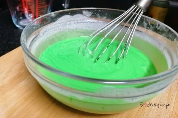 green batter in a bowl and a hand whisk