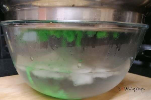 a bowl of iced water and cendol maker over it