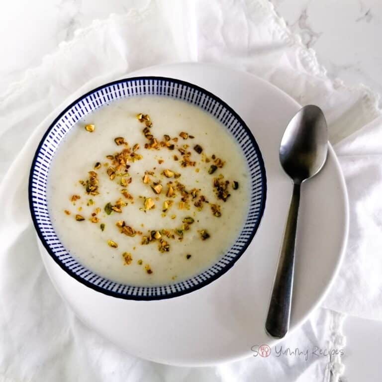 A bowl of Kheer - Pakistani rice pudding and a spoon on a white plate