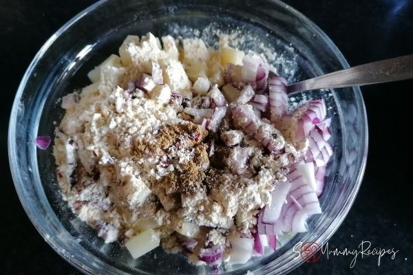 potato cubes, chopped onions, spices and gram flour in a mixing bowl