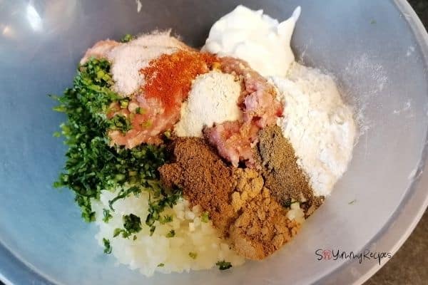 ground chicken with spices and herbs in a mixing bowl