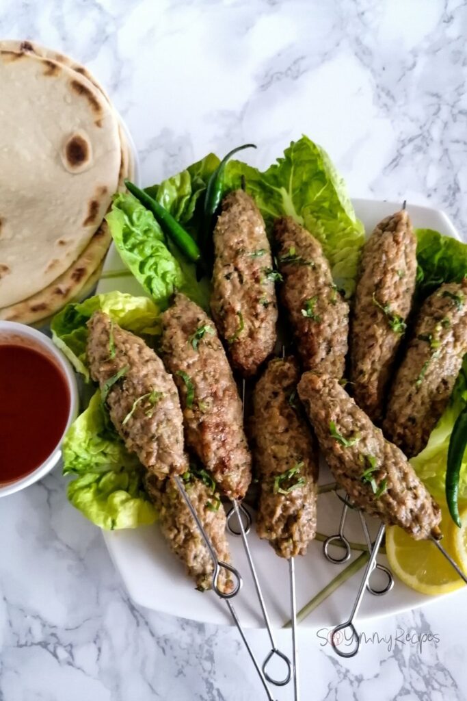a plate of chicken seekh kababs and naan bread and chilli sauce