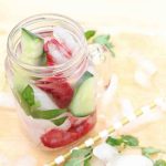 a jar of mint and cucumber water with strawberries.