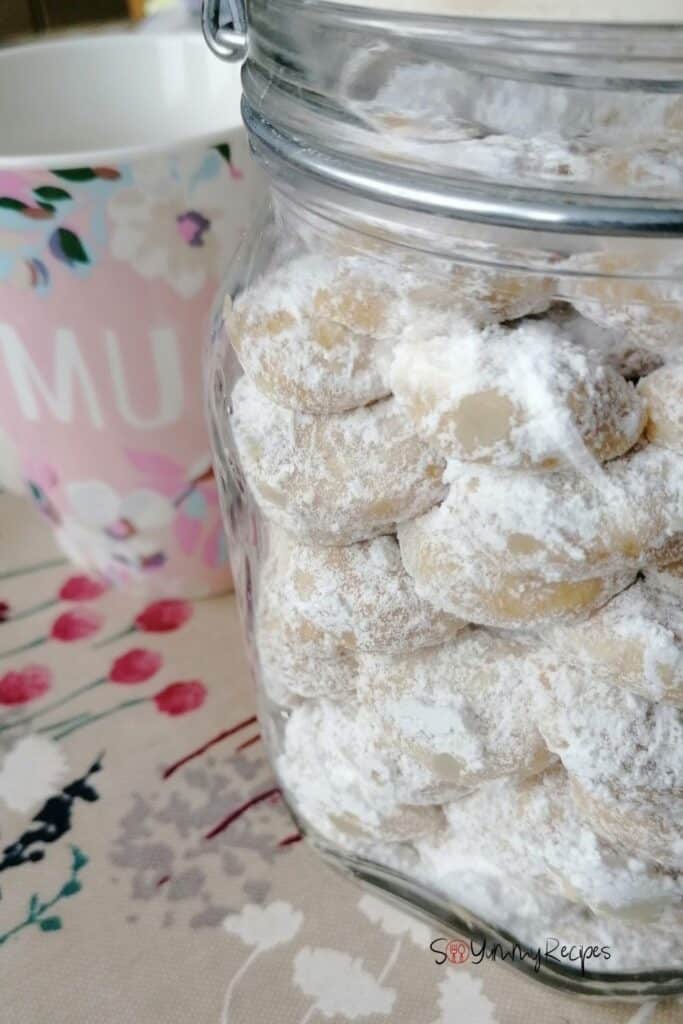 a jar of kue putri salju - Indonesian Snow White Butter Cookies - with a pink mug next to the jar