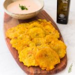 a plate of Carribean Tostones with a small bowl of dipping sauce.