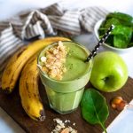 green smoothie with bananas and apple around the glass.