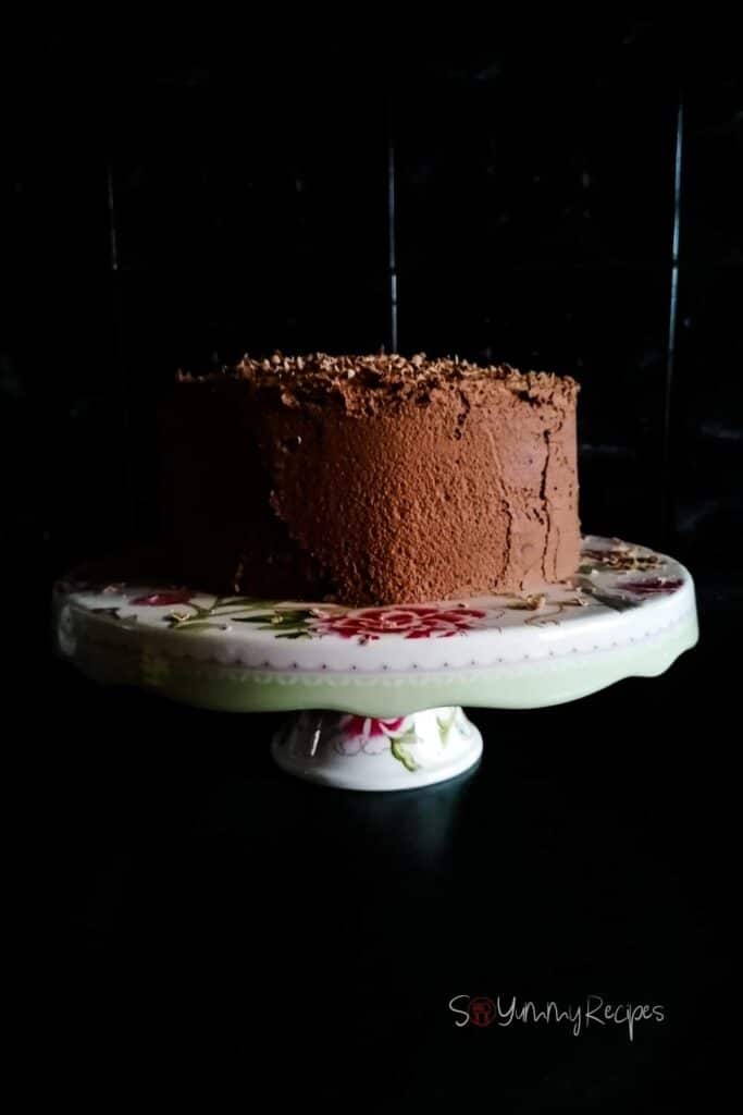 chocolate cake on a white cake stand with black background