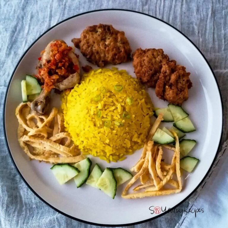 A plate of Nasi Kuning - the Indonesian yellow rice surrounded with chicken, fritters, slices of omelettes and cucumber