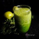 Apple and kale smoothie in a tall glass with apple and kale in the background