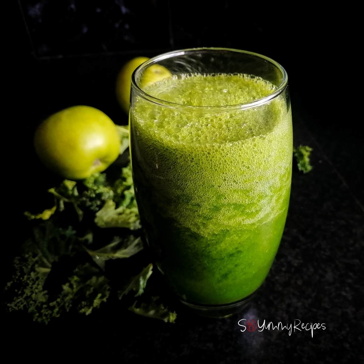 Apple and kale smoothie in a tall glass with apple and kale in the background