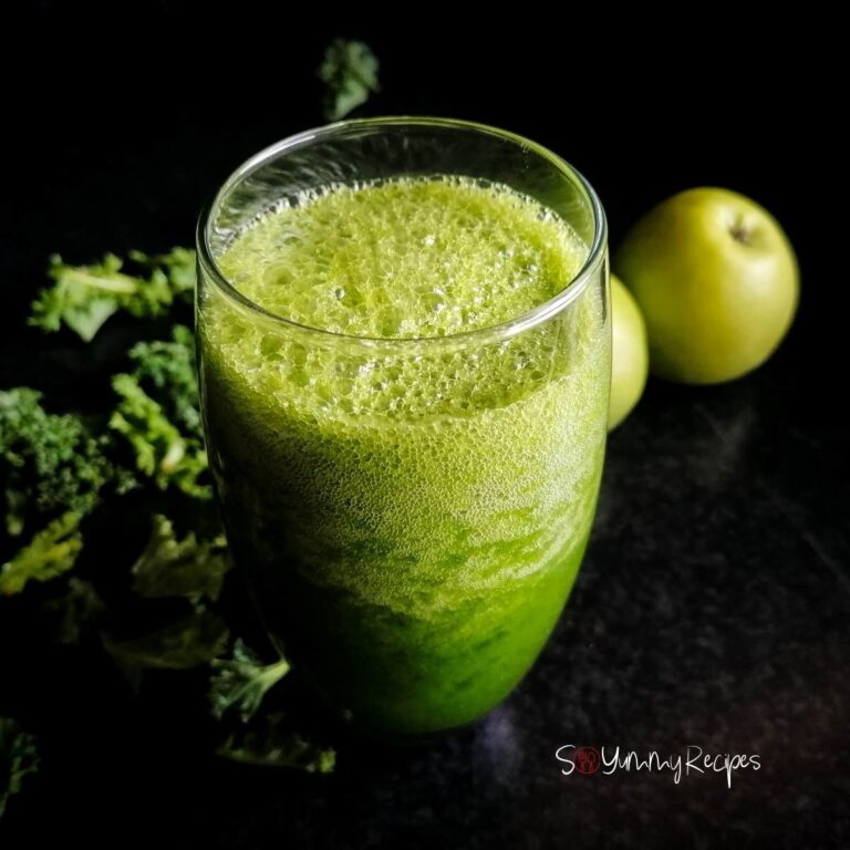 a glass of green apple and kale smoothie with apples and some kale leaves on the background