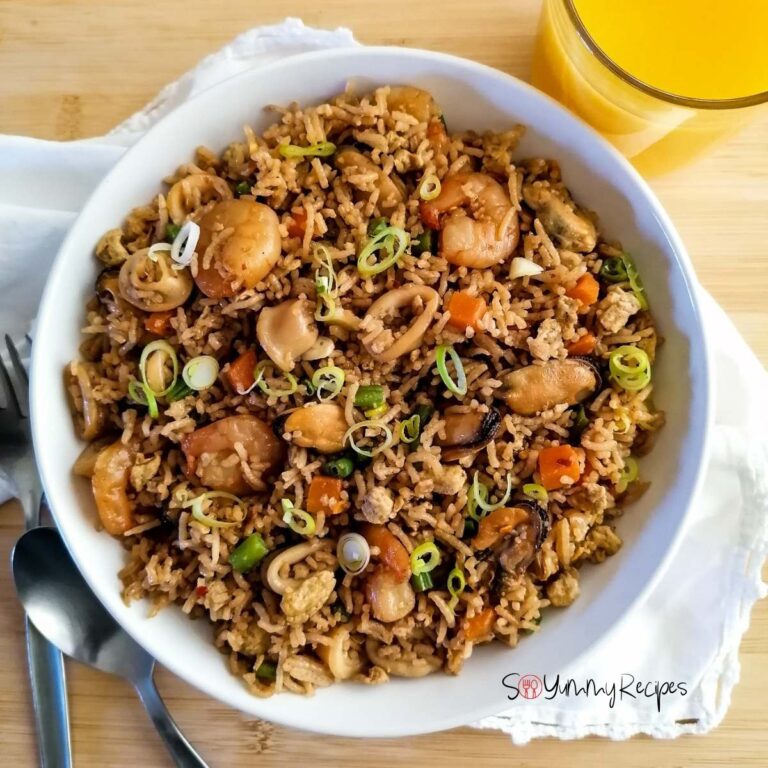 Nasi Goreng Seafood Recipe Indonesian in a white plate with a glass of orange juice on the side