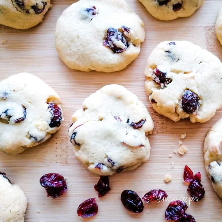white chocolate chip and cranberries cookies on a wooden chopping board