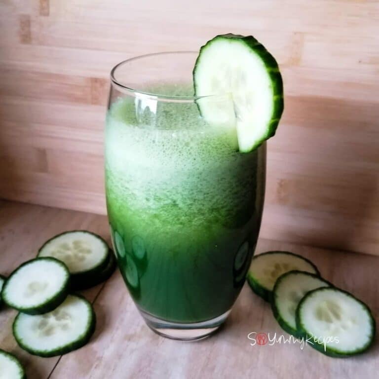 cucumber and kale smoothie in a tall glass with some cucumber slices around