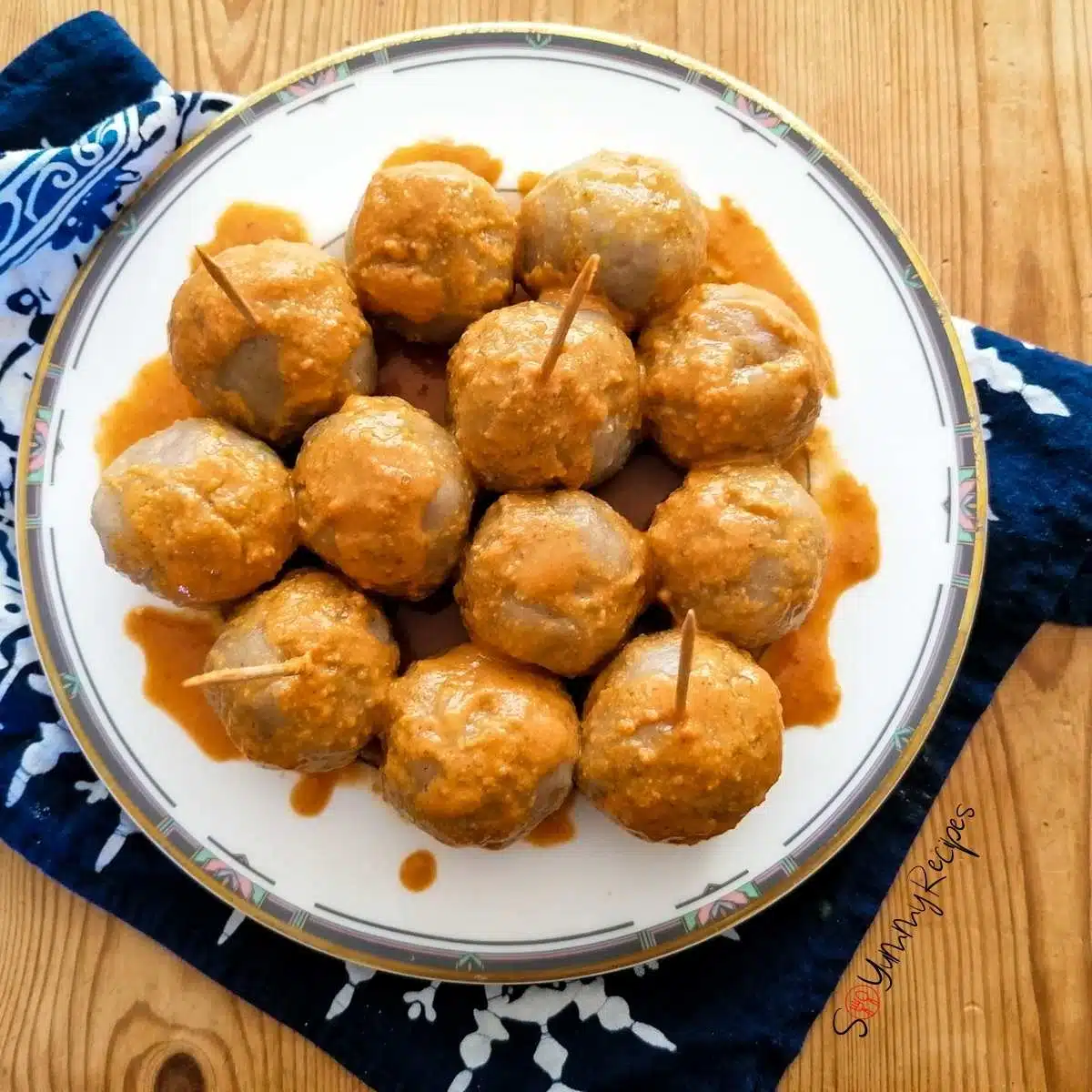 Cilok - Indonesian tapioca dumpling balls - drizzled with spicy peanut sauce on a white plate