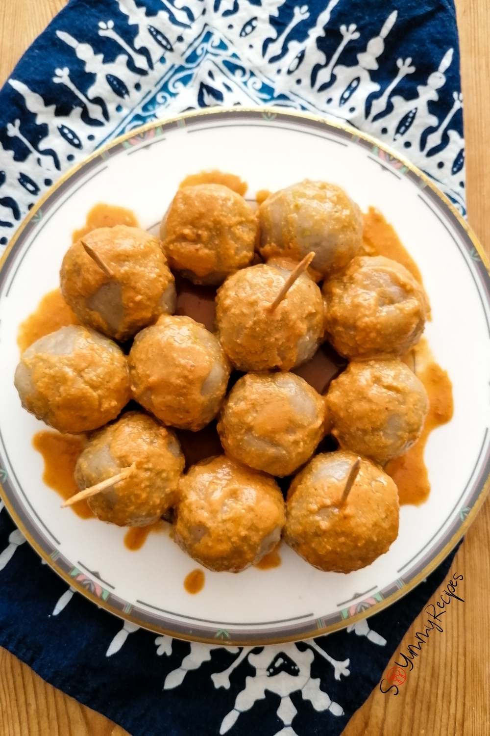 15 balls of Cilok - the chewy tapioca dumplings - on a white plate drizzled with spicy peanut sauce. 