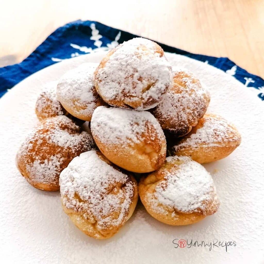 Some Poffertjes - the Dutch mini pancakes - sprinkled with icing sugar on a white plate