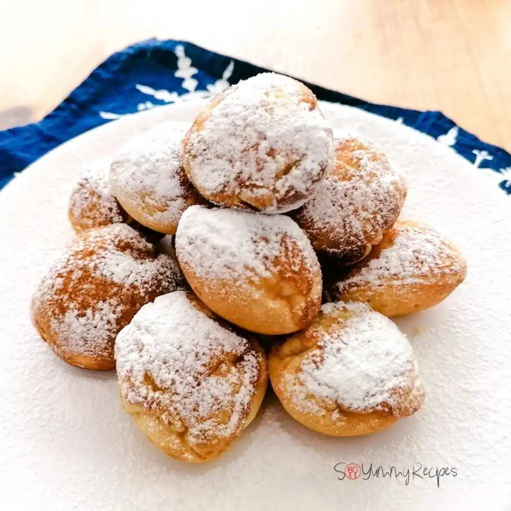 Some Poffertjes - the Dutch mini pancakes - sprinkled with icing sugar on a white plate