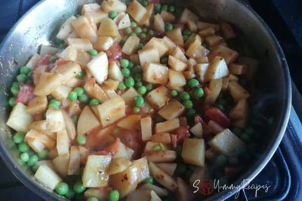 cooking the potato and green peas curry on a pan