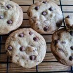 four chewy chocolate chip cookies on a cooling rack