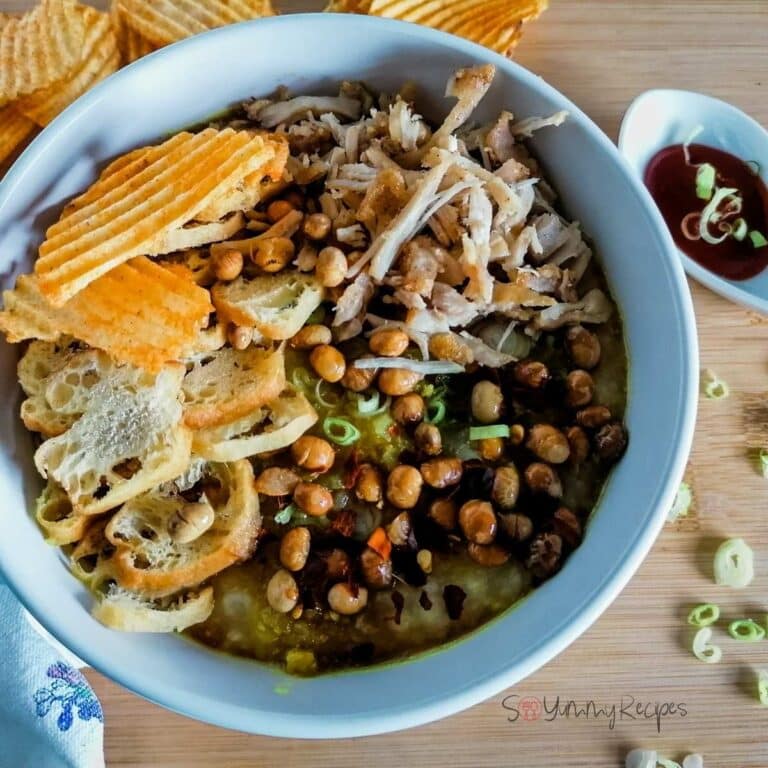A big bowl of Indonesian rice porridge - Bubur Ayam - garnished with shredded chicken, fried soya beans, Cakwe, and some potato crisps.