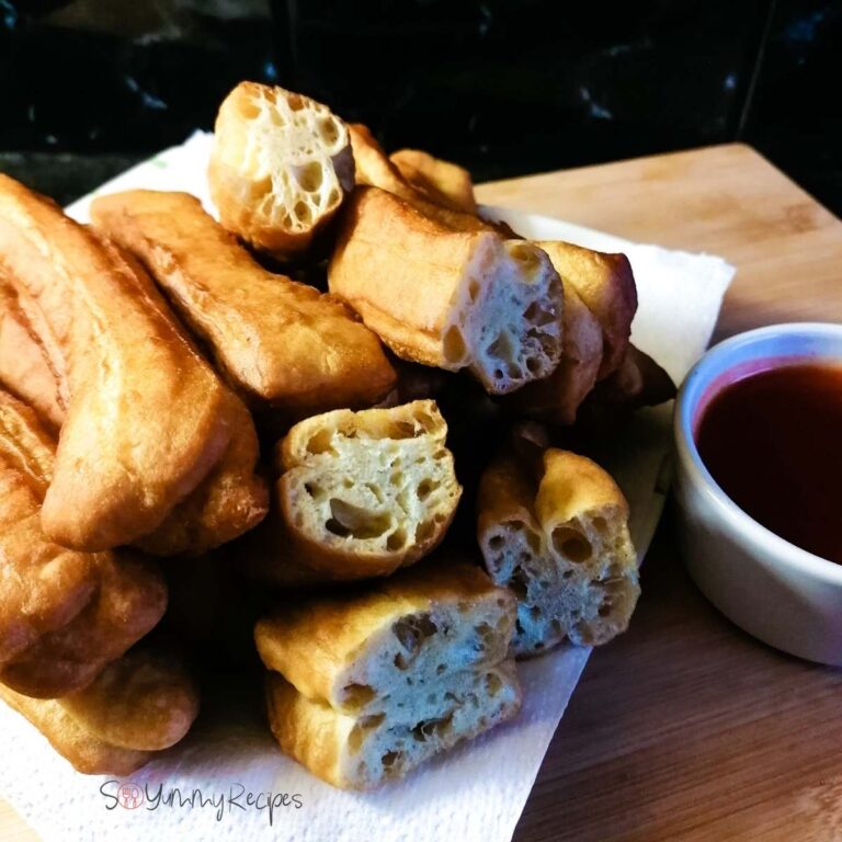 A pile of Indonesian Cakwe with a small bowl of chilli sauce.