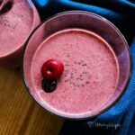 a glass of cherry smoothie with yogurt and no banana with a cherry and a sprinkle of chia seeds on the top.
