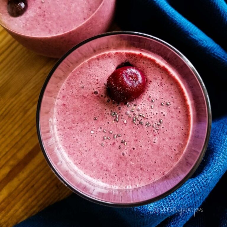 cherry smoothie with yoghurt in glasses with cerry on the top and blue napkin around the glasses.