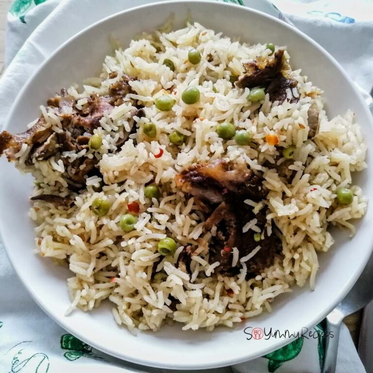 A white plate of Yakhni mutton pulao rice with green peas.