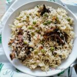 Pakistani Yakhni mutton pulao rice on a white round plate.
