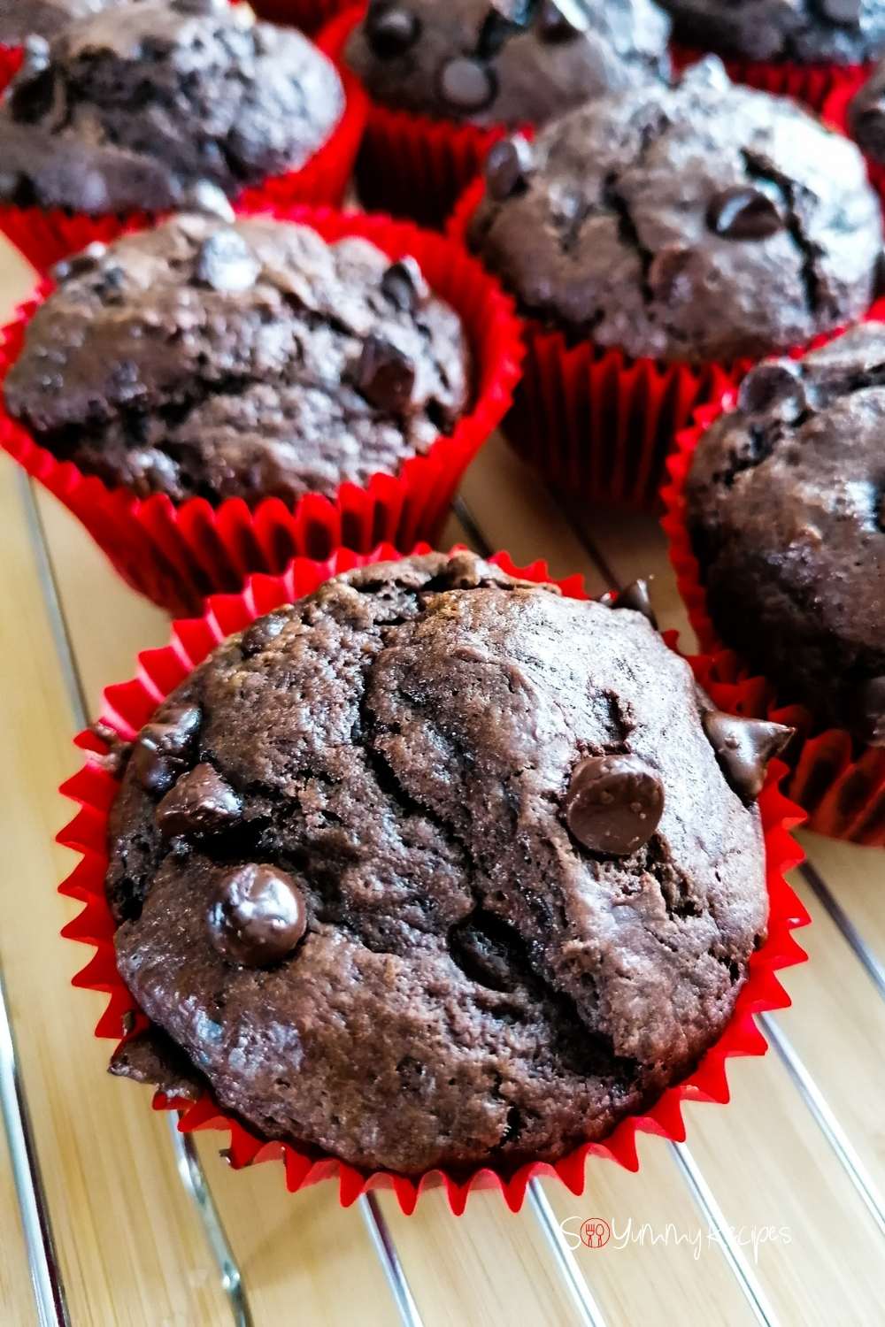 Double chocolate muffins in red paper muffin cases on a wire cooling rack.
